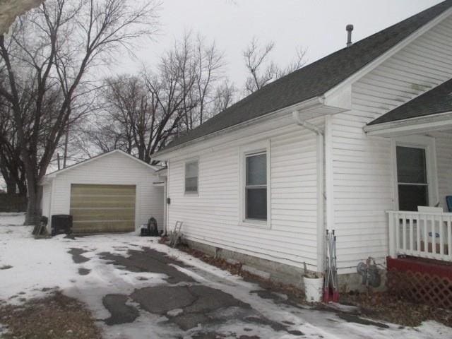 snow covered property featuring an outbuilding and a garage