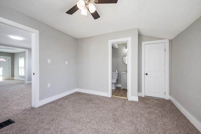 unfurnished bedroom with vaulted ceiling, carpet, ceiling fan, and ensuite bath