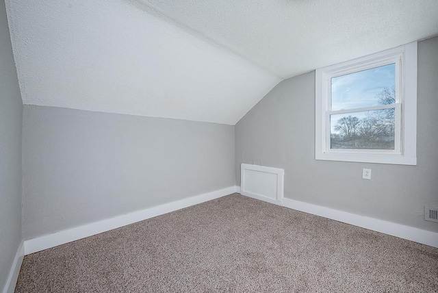 additional living space featuring lofted ceiling, a textured ceiling, and carpet flooring