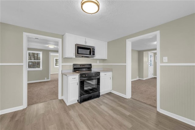 kitchen with white cabinets, light carpet, electric range, and a textured ceiling