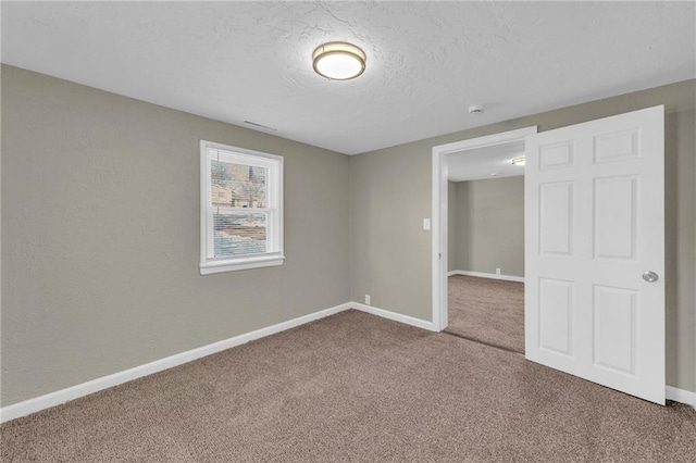 unfurnished room with carpet and a textured ceiling