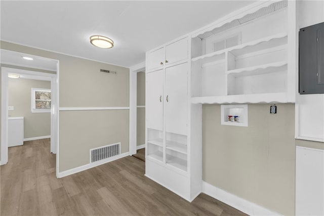 clothes washing area with hookup for a washing machine, electric panel, and light hardwood / wood-style flooring