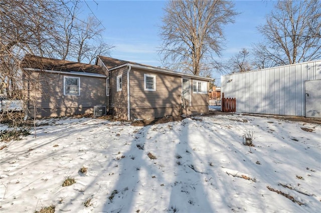 snow covered rear of property featuring central AC