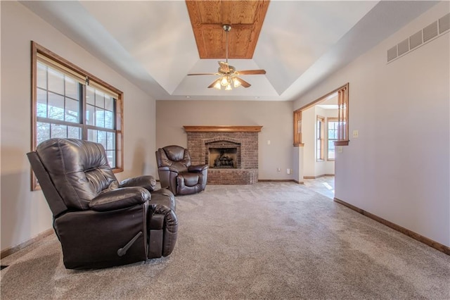 living room with lofted ceiling, light colored carpet, a tray ceiling, ceiling fan, and a fireplace