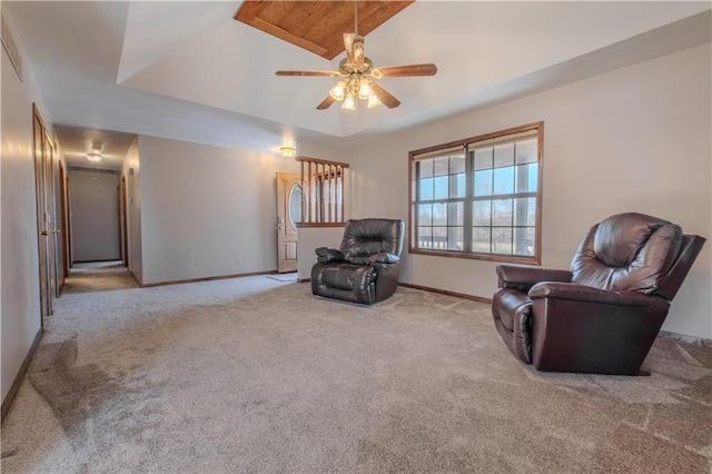 sitting room featuring vaulted ceiling, light colored carpet, ceiling fan, and a tray ceiling