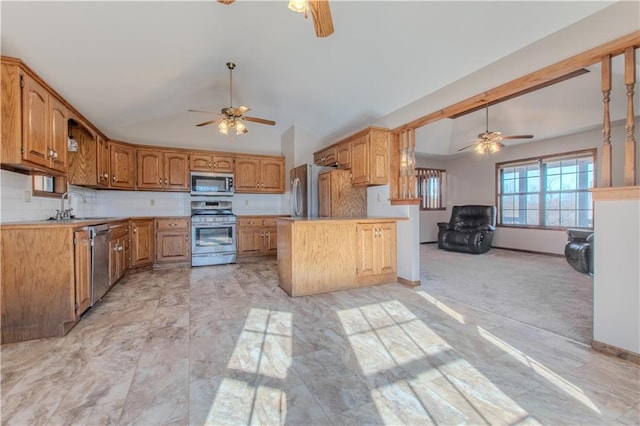 kitchen with appliances with stainless steel finishes, lofted ceiling, sink, decorative backsplash, and a center island