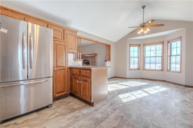 kitchen featuring ceiling fan, lofted ceiling, stainless steel refrigerator, and kitchen peninsula