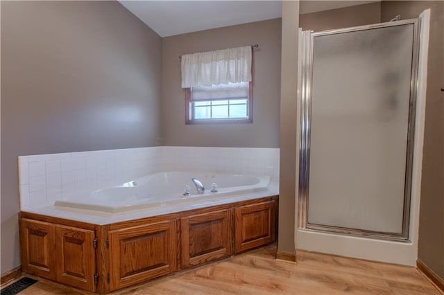 bathroom with wood-type flooring and plus walk in shower