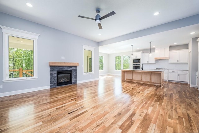 unfurnished living room featuring a ceiling fan, recessed lighting, baseboards, and light wood finished floors