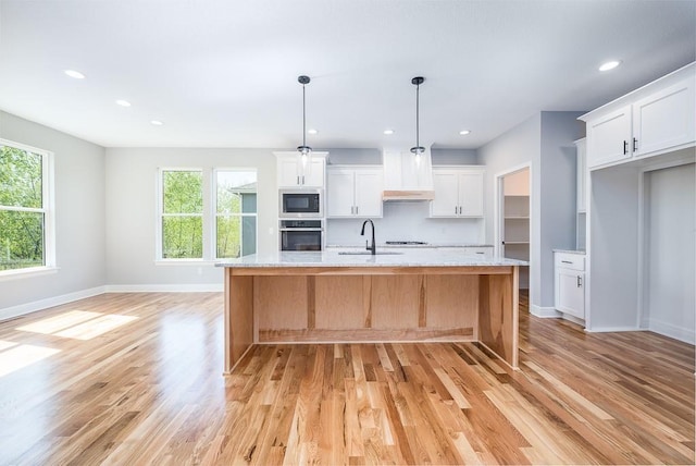 kitchen with white cabinets, light stone counters, oven, a kitchen island with sink, and black microwave