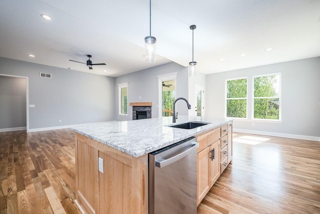 kitchen featuring light brown cabinets, a sink, visible vents, dishwasher, and a center island with sink