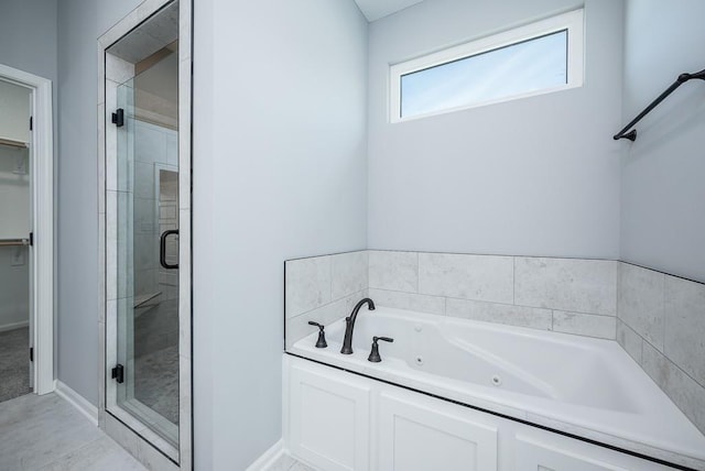 bathroom with baseboards, a stall shower, a walk in closet, and a jetted tub