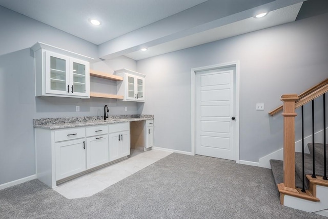 kitchen with open shelves, glass insert cabinets, white cabinets, light carpet, and light stone countertops