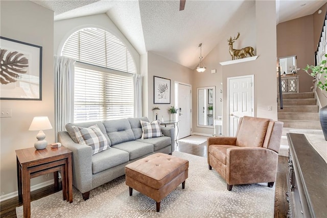 living room with light hardwood / wood-style flooring, high vaulted ceiling, and a textured ceiling