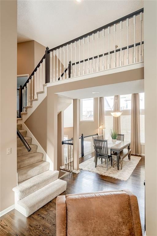 staircase with a towering ceiling and hardwood / wood-style floors