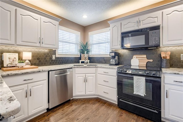 kitchen featuring white cabinetry, tasteful backsplash, wood-type flooring, light stone countertops, and black appliances