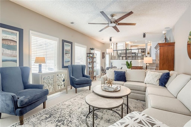 living room featuring ceiling fan and a textured ceiling