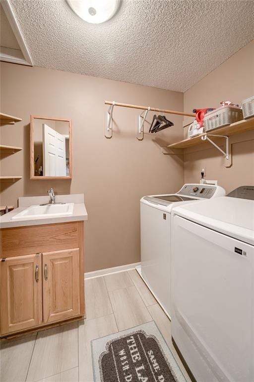 laundry room featuring cabinets, sink, a textured ceiling, and independent washer and dryer