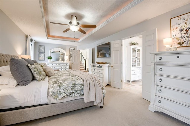 carpeted bedroom with a tray ceiling, a textured ceiling, and ceiling fan