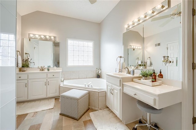 bathroom featuring a relaxing tiled tub, vanity, lofted ceiling, and ceiling fan