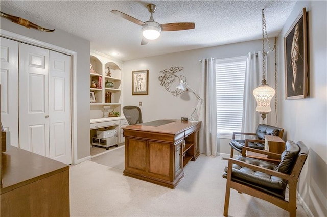 home office featuring ceiling fan, light colored carpet, built in features, and a textured ceiling