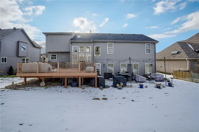 snow covered rear of property with a wooden deck