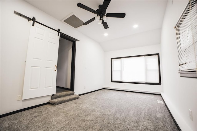 unfurnished bedroom featuring ceiling fan, carpet flooring, lofted ceiling, and a barn door