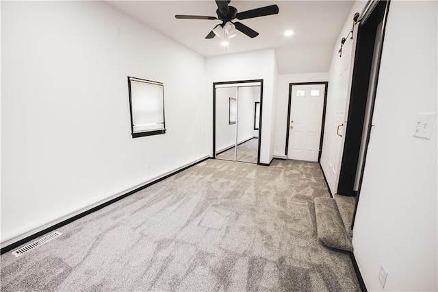 unfurnished bedroom featuring light carpet, a barn door, and ceiling fan