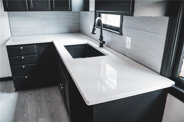 kitchen featuring dark hardwood / wood-style flooring, sink, backsplash, and light stone counters