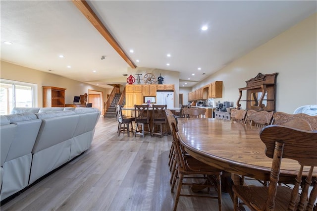 dining space featuring lofted ceiling with beams and light hardwood / wood-style floors