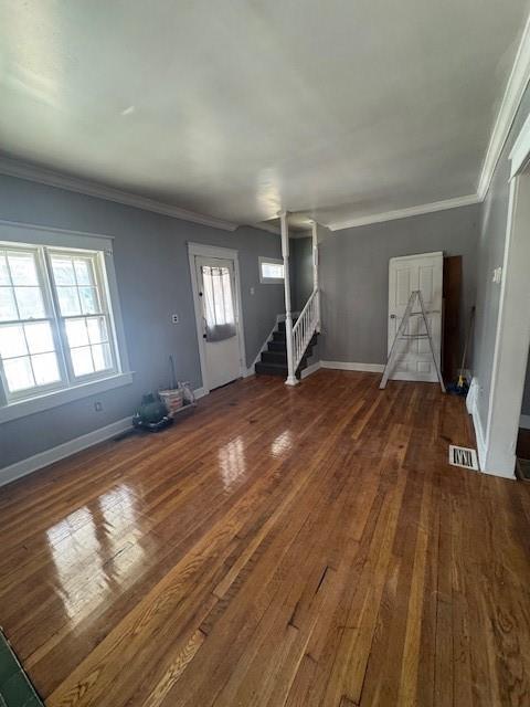 unfurnished living room featuring ornamental molding and dark hardwood / wood-style flooring