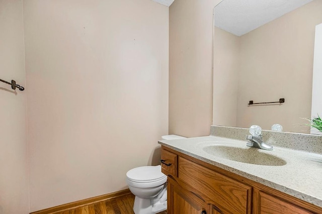 bathroom featuring hardwood / wood-style flooring, toilet, and vanity