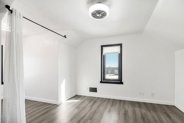 additional living space with hardwood / wood-style floors and lofted ceiling