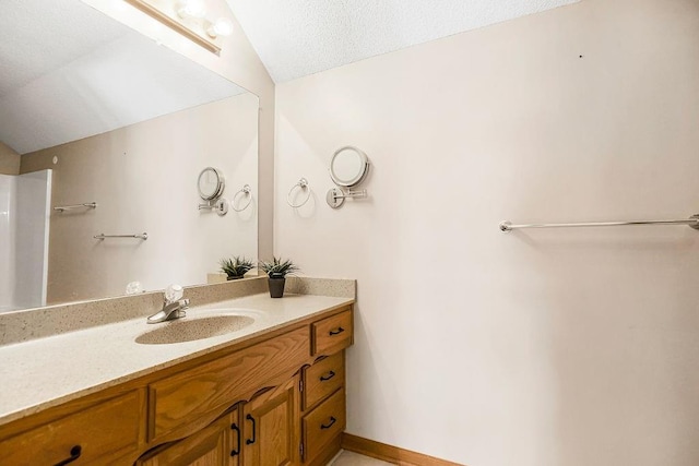 bathroom with a textured ceiling, vaulted ceiling, and vanity