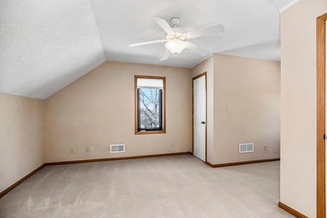 additional living space featuring ceiling fan, a textured ceiling, light carpet, and lofted ceiling