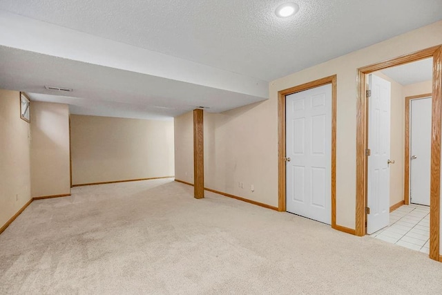 basement featuring light colored carpet and a textured ceiling