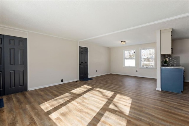 unfurnished living room featuring crown molding and dark hardwood / wood-style flooring