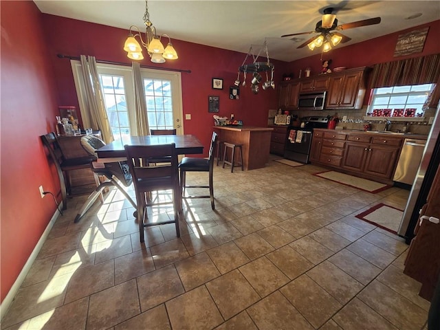 dining area featuring ceiling fan with notable chandelier, tile patterned floors, and sink