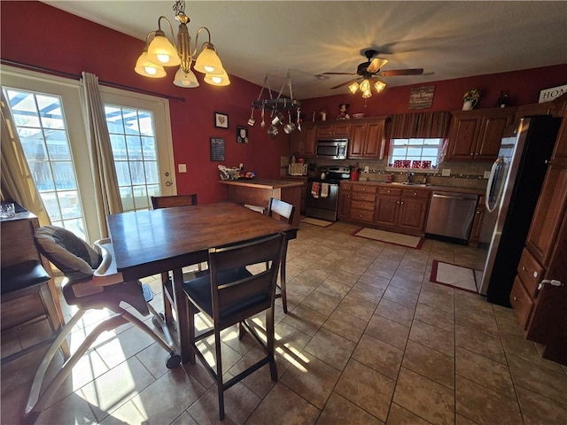 tiled dining room with sink and ceiling fan with notable chandelier