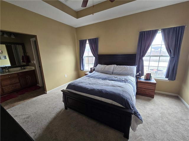 bedroom with carpet, connected bathroom, ceiling fan, and a tray ceiling