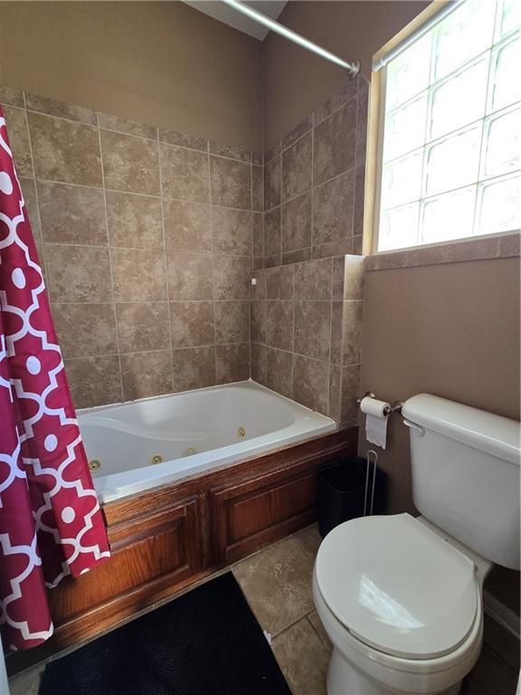 bathroom featuring toilet, tile patterned flooring, and shower / bath combo with shower curtain