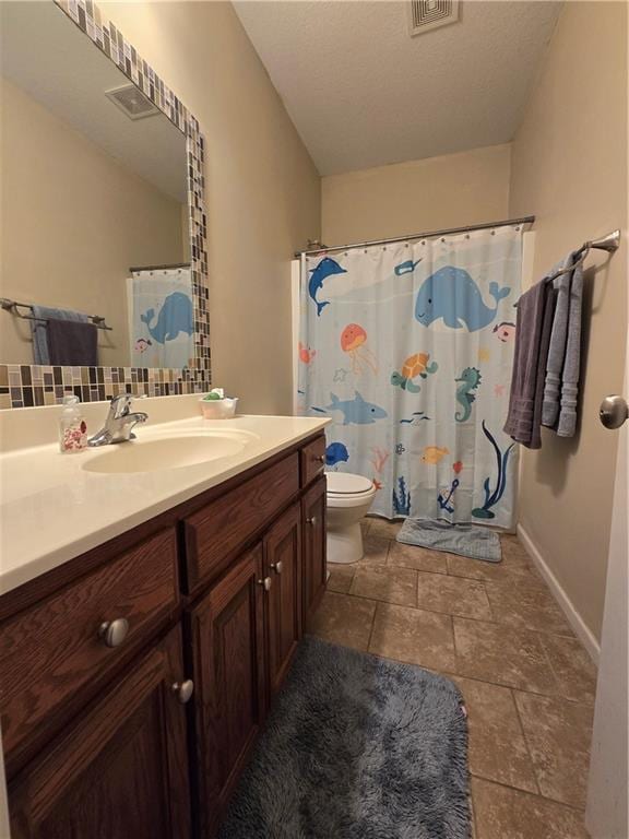 bathroom with vanity, tasteful backsplash, and toilet