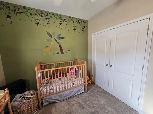 bedroom featuring a crib, carpet flooring, ceiling fan, and a closet