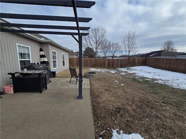 yard covered in snow with an outdoor fire pit and a patio area