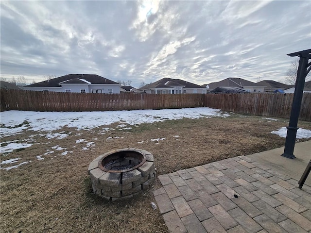 yard layered in snow with an outdoor fire pit and a patio area