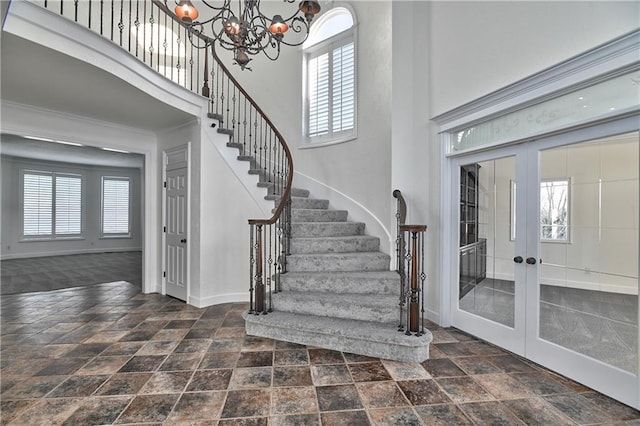 foyer entrance with a notable chandelier, a towering ceiling, and french doors