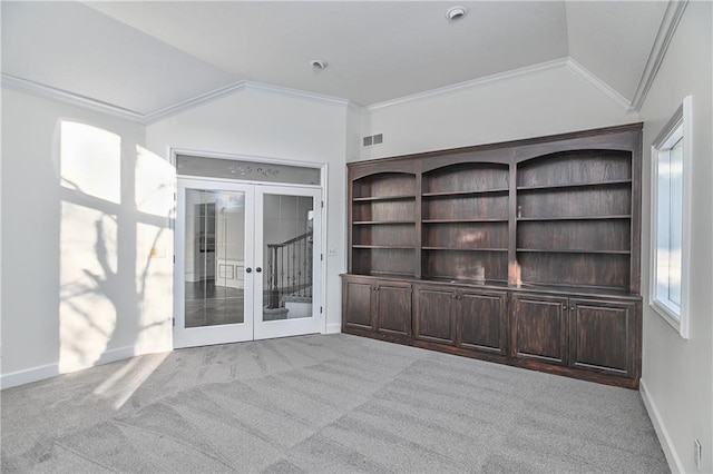 unfurnished living room with french doors, light colored carpet, ornamental molding, and lofted ceiling