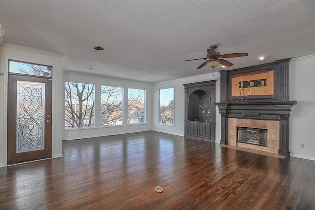 unfurnished living room with a tile fireplace, dark hardwood / wood-style floors, crown molding, and a textured ceiling