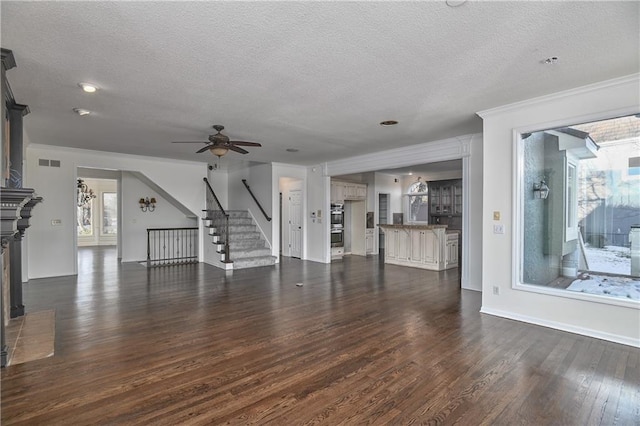 unfurnished living room with crown molding, a textured ceiling, dark hardwood / wood-style floors, and ceiling fan