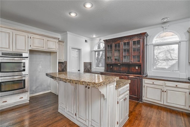 kitchen featuring crown molding, a breakfast bar, a kitchen island, dark hardwood / wood-style flooring, and stainless steel double oven